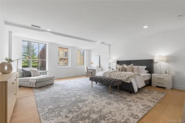 a spacious bedroom with a bed a couch and large window