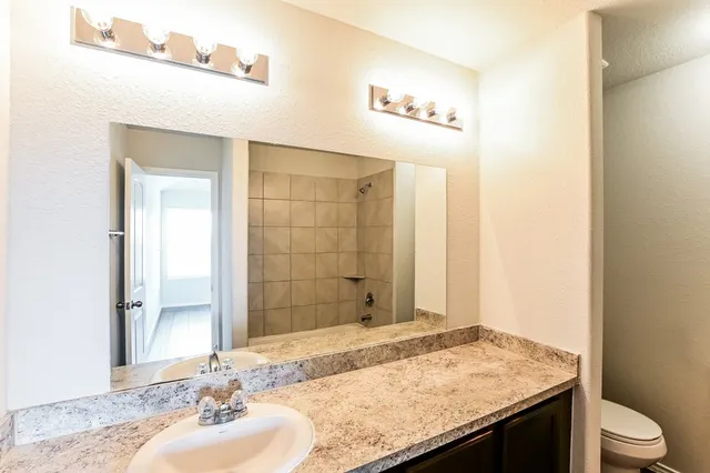 a bathroom with a granite countertop sink toilet and shower