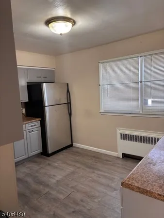 a view of a refrigerator in kitchen and an empty room