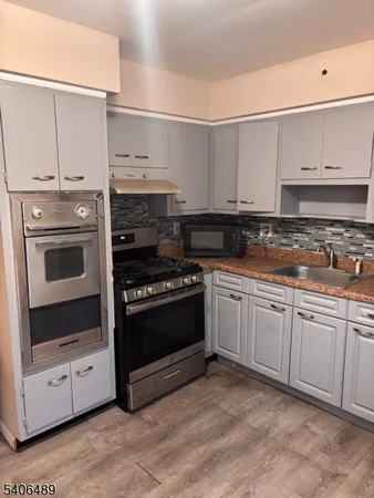 a kitchen with stainless steel appliances granite countertop a stove and white cabinets