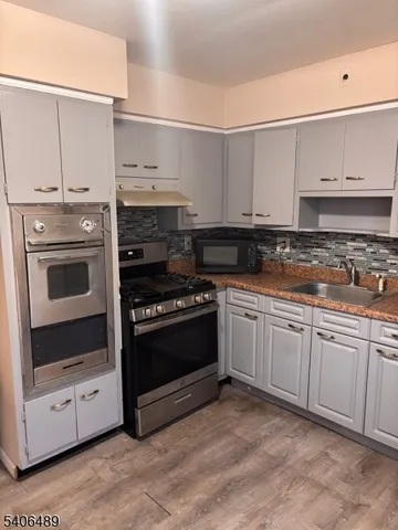 a kitchen with stainless steel appliances granite countertop a stove and white cabinets