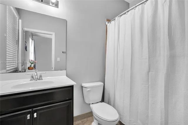 a bathroom with a sink a toilet a mirror and shower curtain