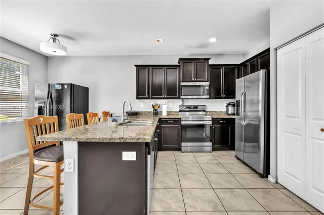 a kitchen with stainless steel appliances granite countertop a refrigerator oven a sink dishwasher and white cabinets with wooden floor