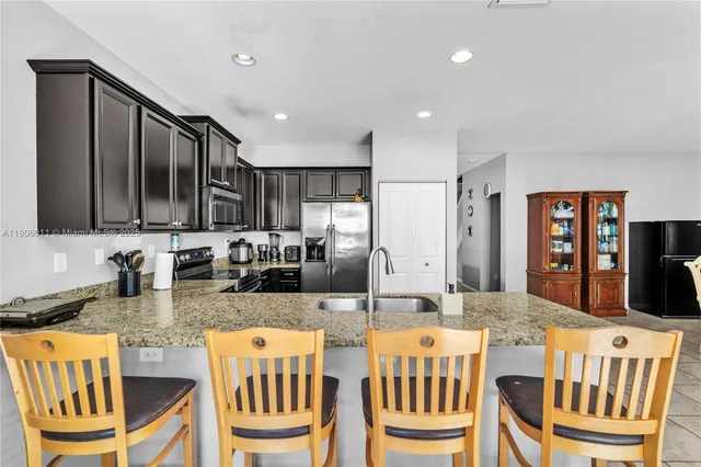 a dining hall with stainless steel appliances granite countertop a dining table and chairs