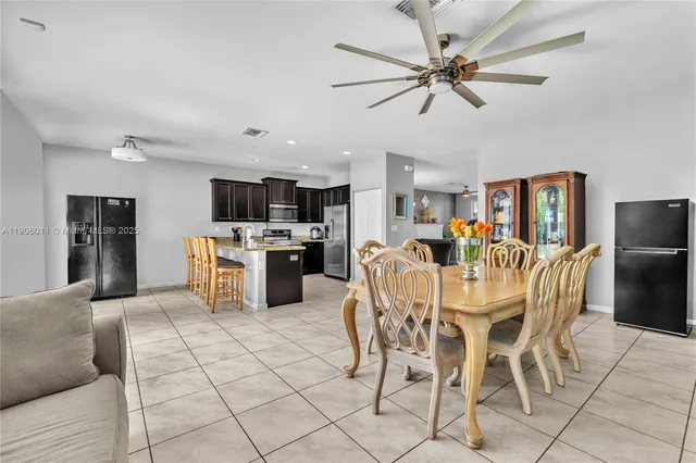 a kitchen with stainless steel appliances kitchen island granite countertop a refrigerator a stove top oven a sink dishwasher and a dining table with wooden floor