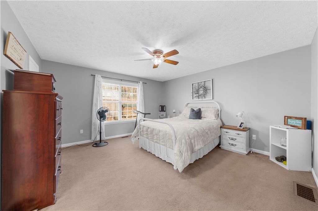 6124 Clyde Conner Road Murrayville, GA 30564 - Photo 18 of 48 a spacious bedroom with a bed and a chandelier