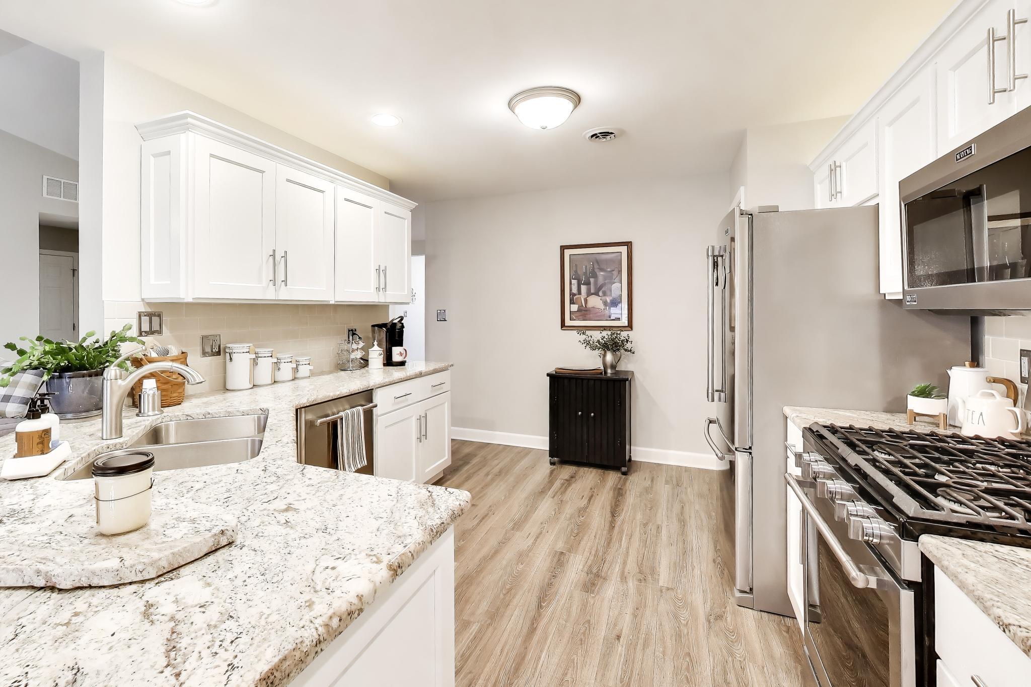 900 A Easy Street Crown Point, IN 46307 - Photo 10 of 22 a kitchen with stainless steel appliances granite countertop a stove top oven a sink dishwasher and a refrigerator with wooden floor