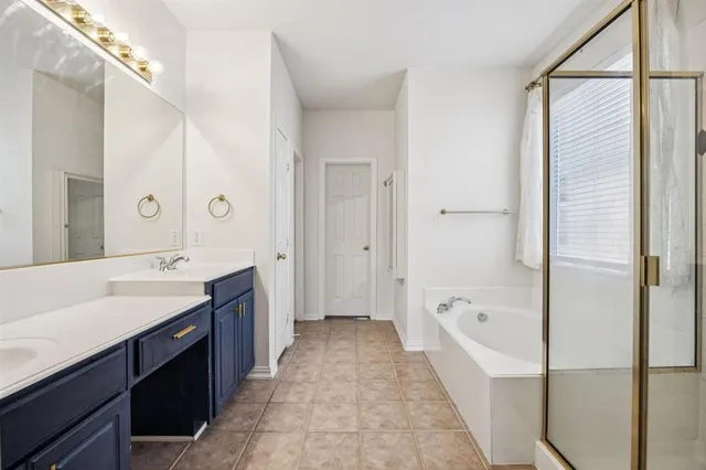 a spacious bathroom with a tub sink shower and mirror