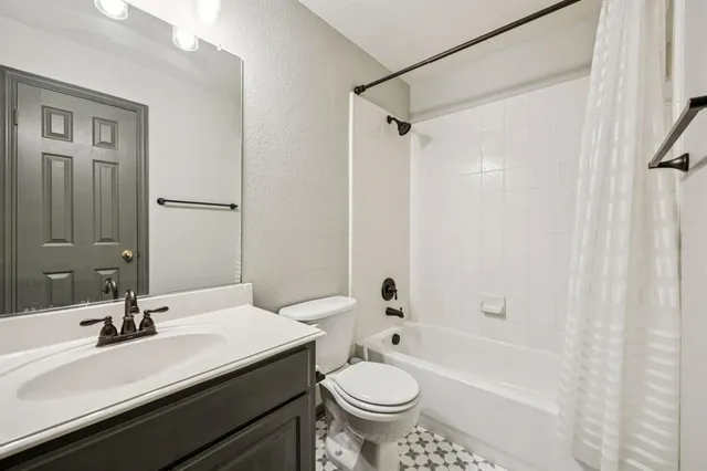 a bathroom with a sink a toilet a mirror a bathtub and shower