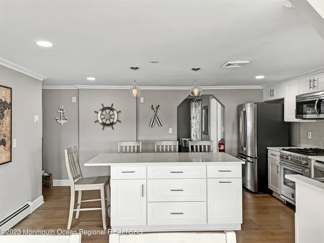 a kitchen with stainless steel appliances granite countertop a dining table chairs refrigerator and microwave