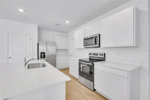 a kitchen with stainless steel appliances granite countertop a sink a stove and a refrigerator with wooden floor