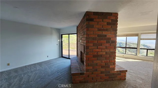a view of an empty room with fireplace and a window