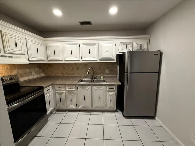 a kitchen with granite countertop a refrigerator sink stove and cabinets