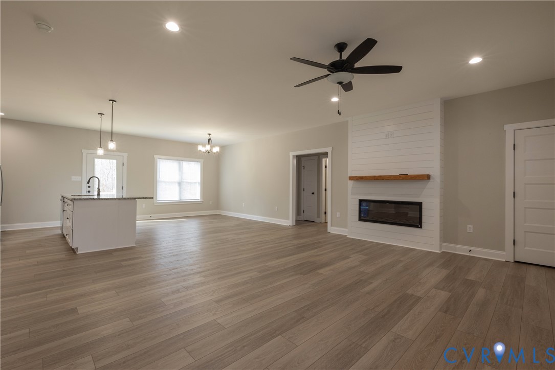 2223 Ridge Road Arvonia, VA 23004 - Photo 13 of 45 an empty room with wooden floor a ceiling fan a fireplace and windows