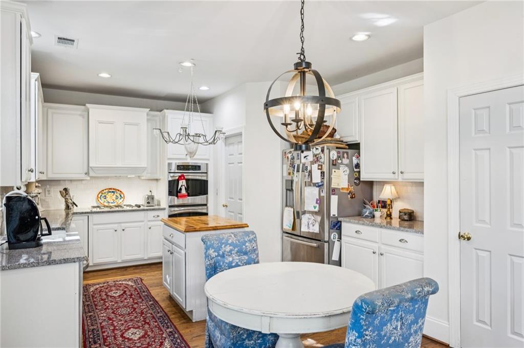 1055 Brookhaven Walk Northeast Atlanta, GA 30319 - Photo 27 of 40 a kitchen with stainless steel appliances a stove a sink dishwasher a dining table and chairs with wooden floor
