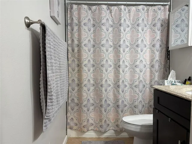 a bathroom with a granite countertop toilet and a sink