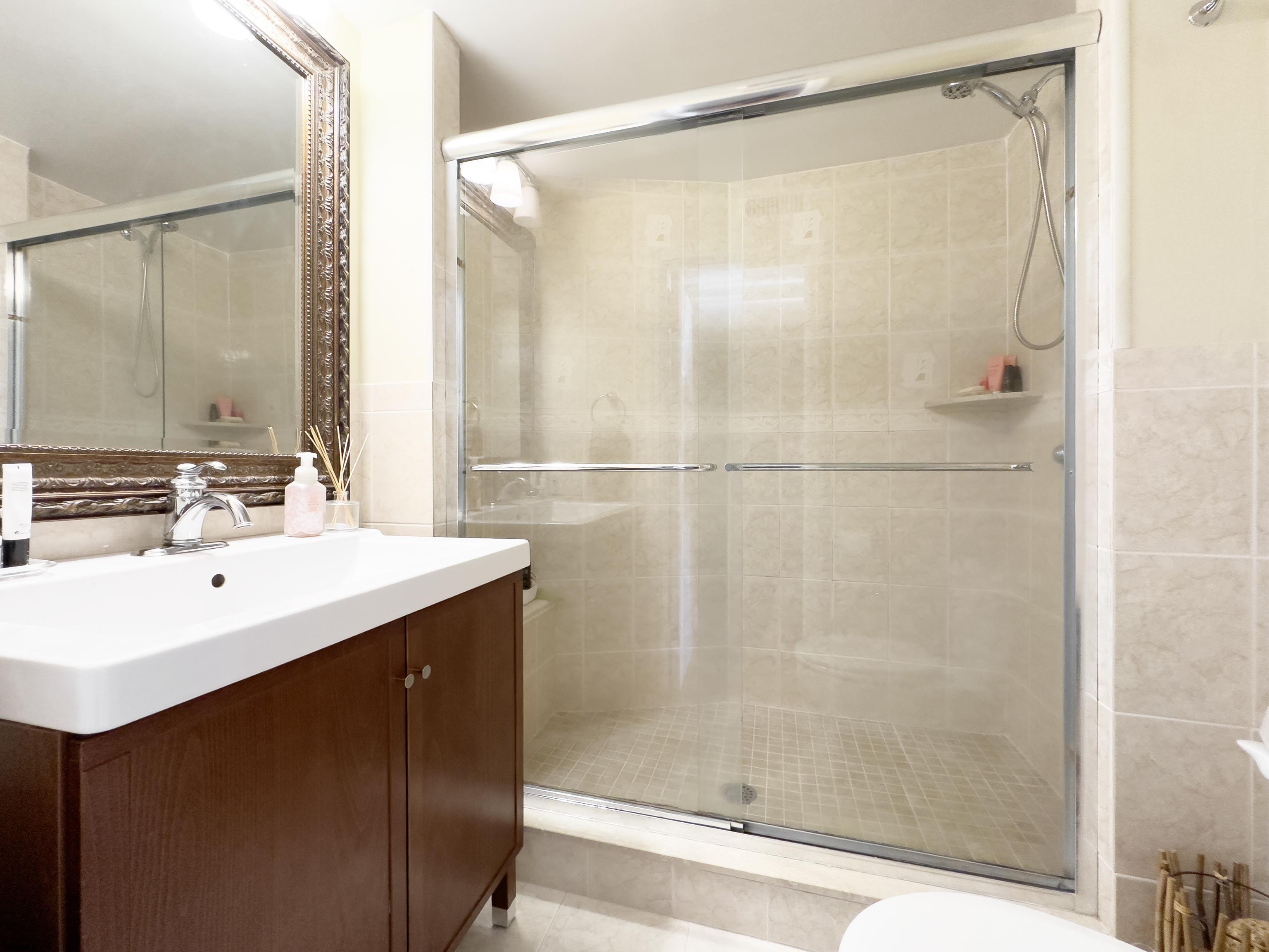 9801 Ventnor Avenue, Unit B1 Margate City, NJ 08402 - Photo 16 of 23 a bathroom with a shower sink vanity and a mirror