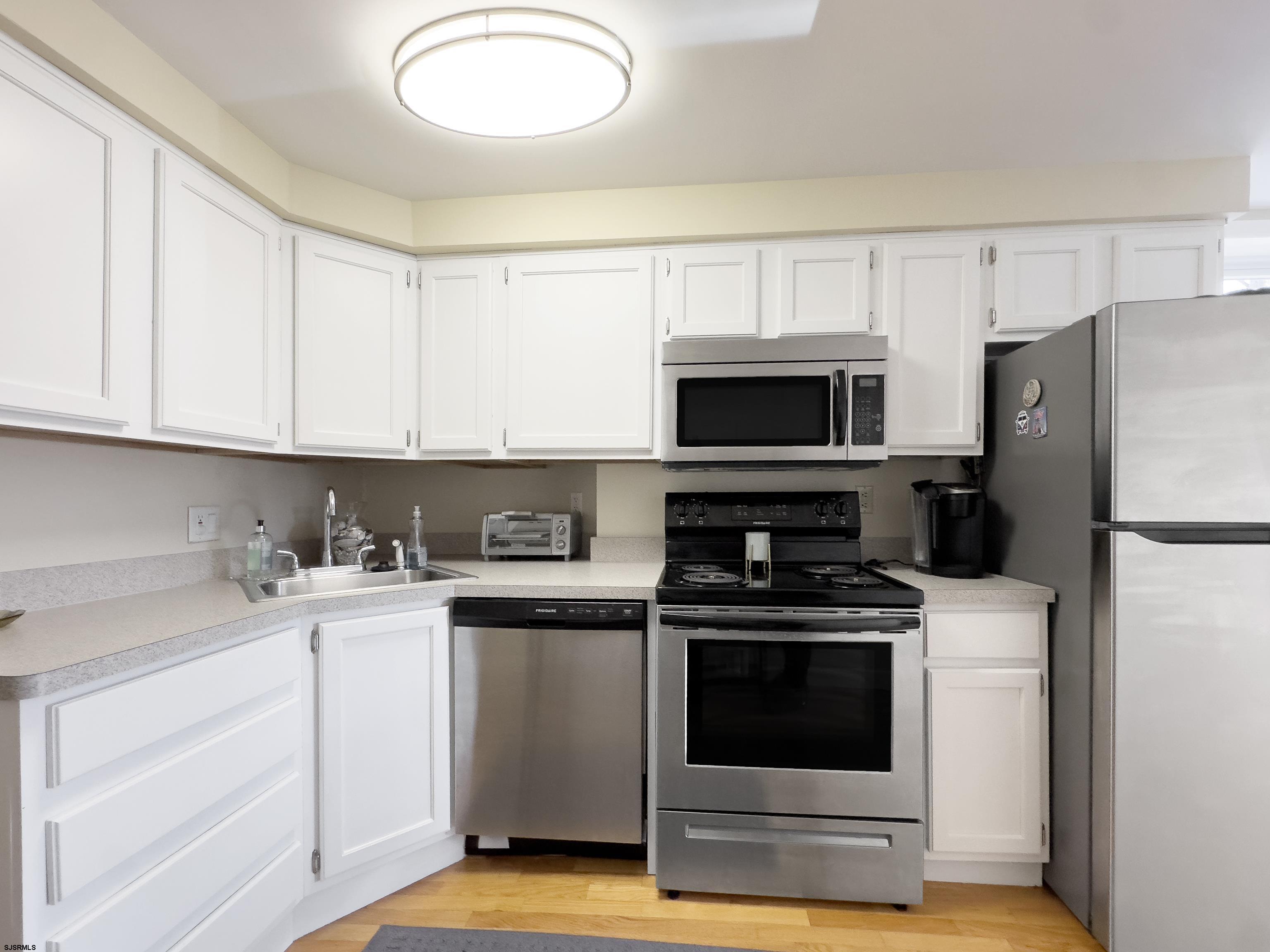 9801 Ventnor Avenue, Unit B1 Margate City, NJ 08402 - Photo 2 of 23 a kitchen with a stove a sink and a microwave