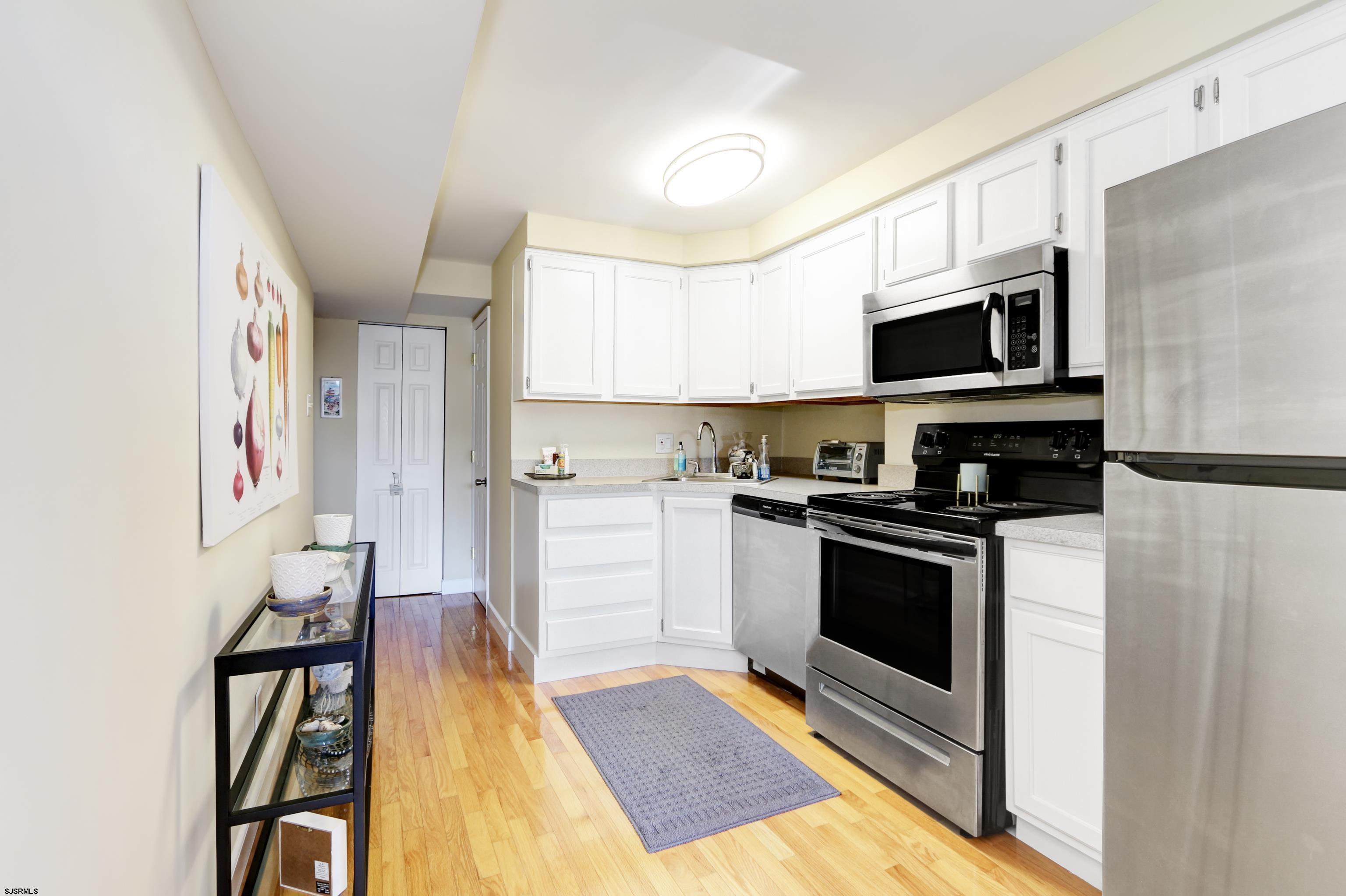 9801 Ventnor Avenue, Unit B1 Margate City, NJ 08402 - Photo 4 of 23 a kitchen with stainless steel appliances kitchen island granite countertop a stove a sink and a microwave