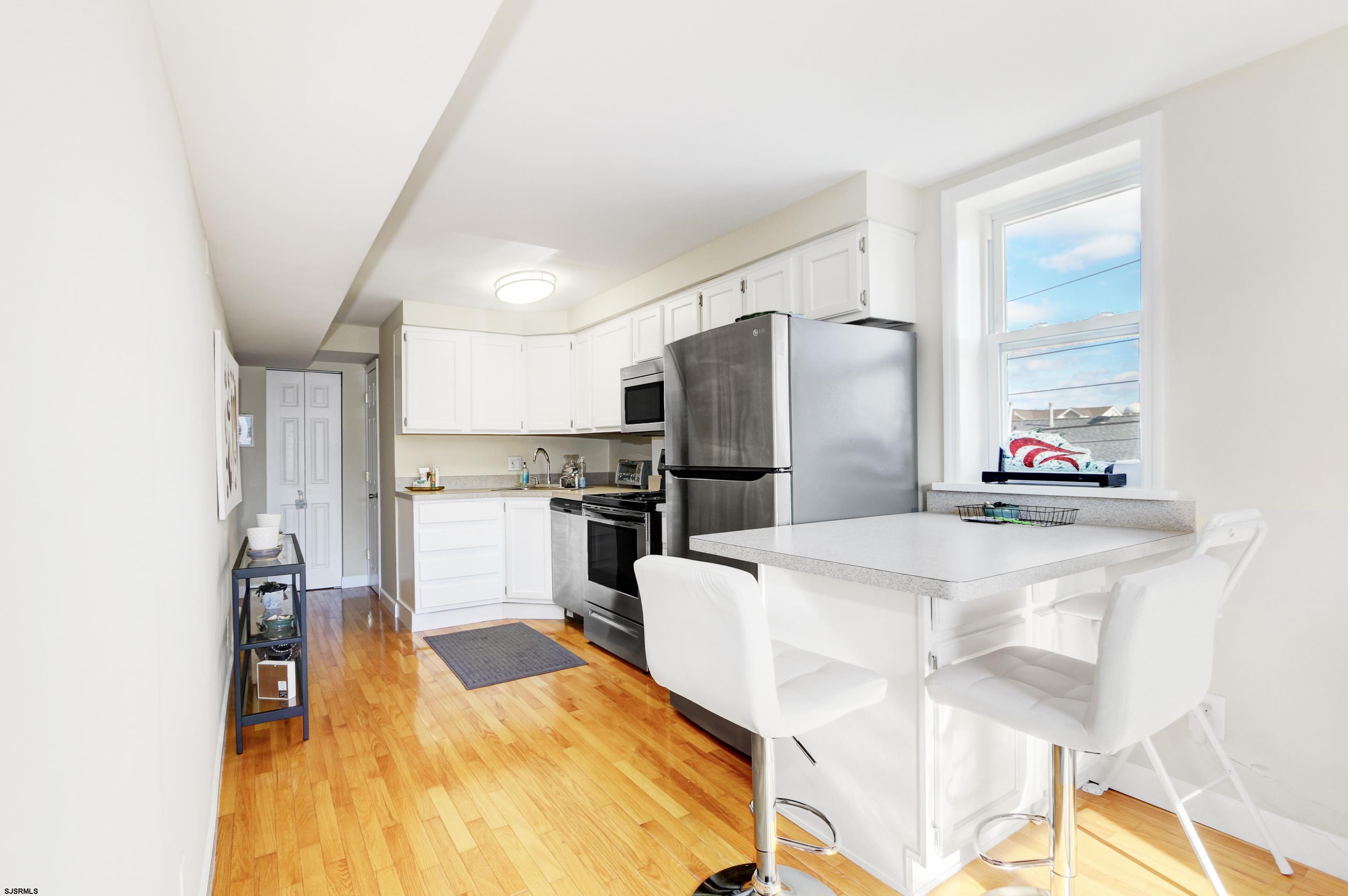 9801 Ventnor Avenue, Unit B1 Margate City, NJ 08402 - Photo 6 of 23 a kitchen with refrigerator and white cabinets