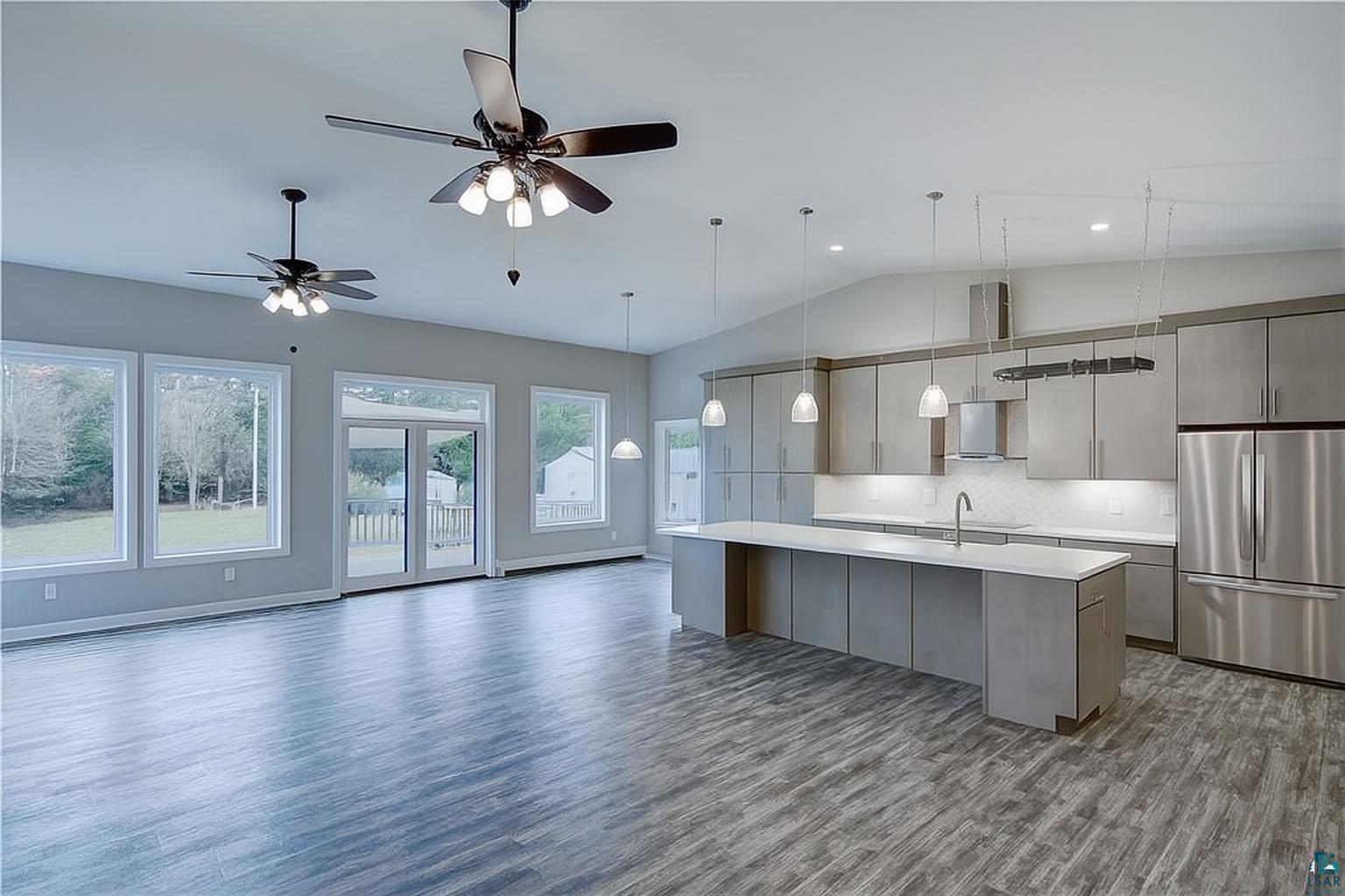 6030 Mitchell Road Iron River, WI 54847 - Photo 11 of 45 Kitchen with freestanding refrigerator, an island with sink, dark wood-style flooring, decorative backsplash, and lofted ceiling