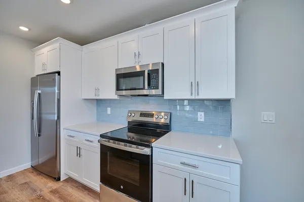 a kitchen with stainless steel appliances granite countertop white cabinets a microwave a sink and refrigerator