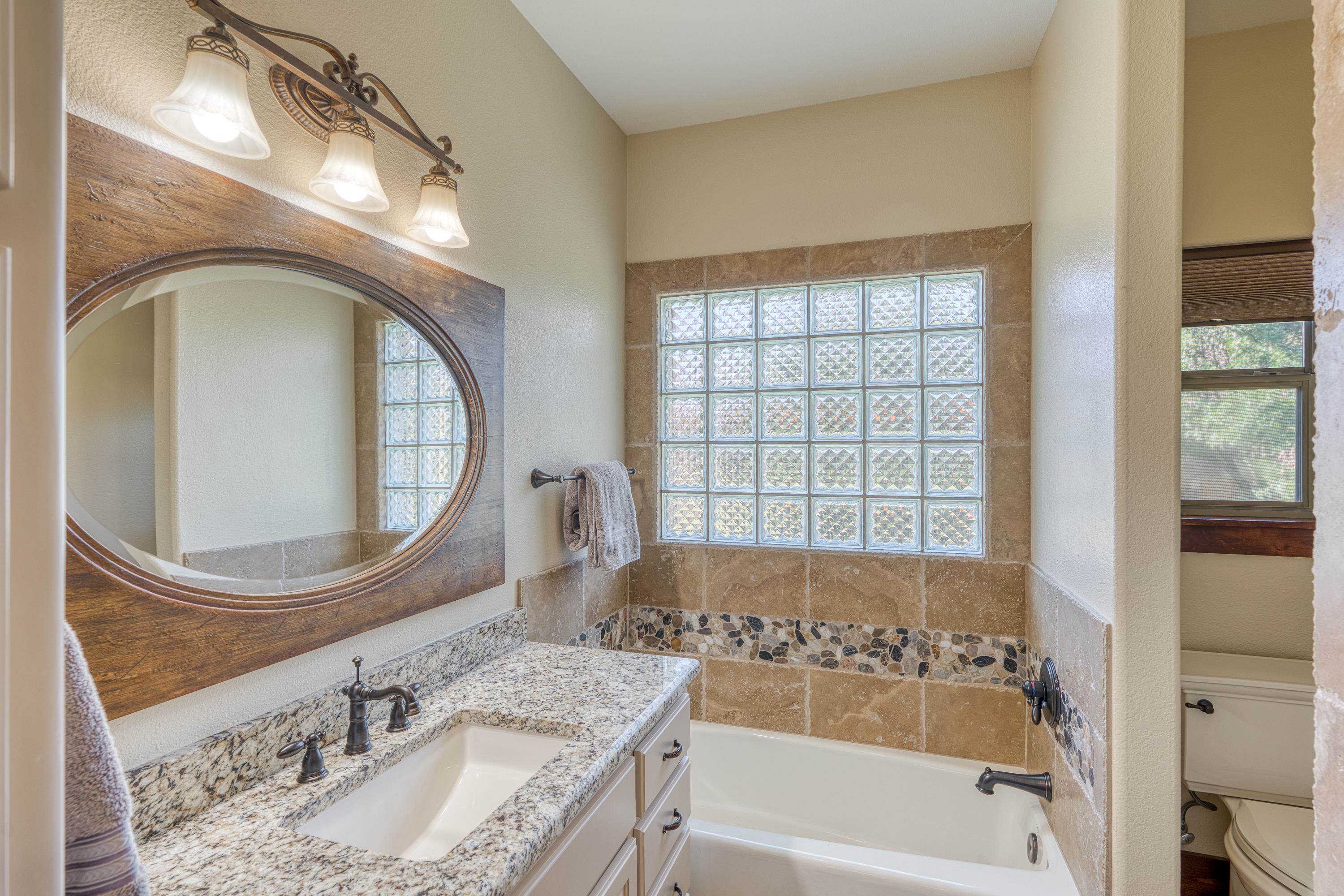 206 River Ranch Road Kingsland, TX 78639 - Photo 12 of 30 a bathroom with a granite countertop sink a mirror and a bathtub