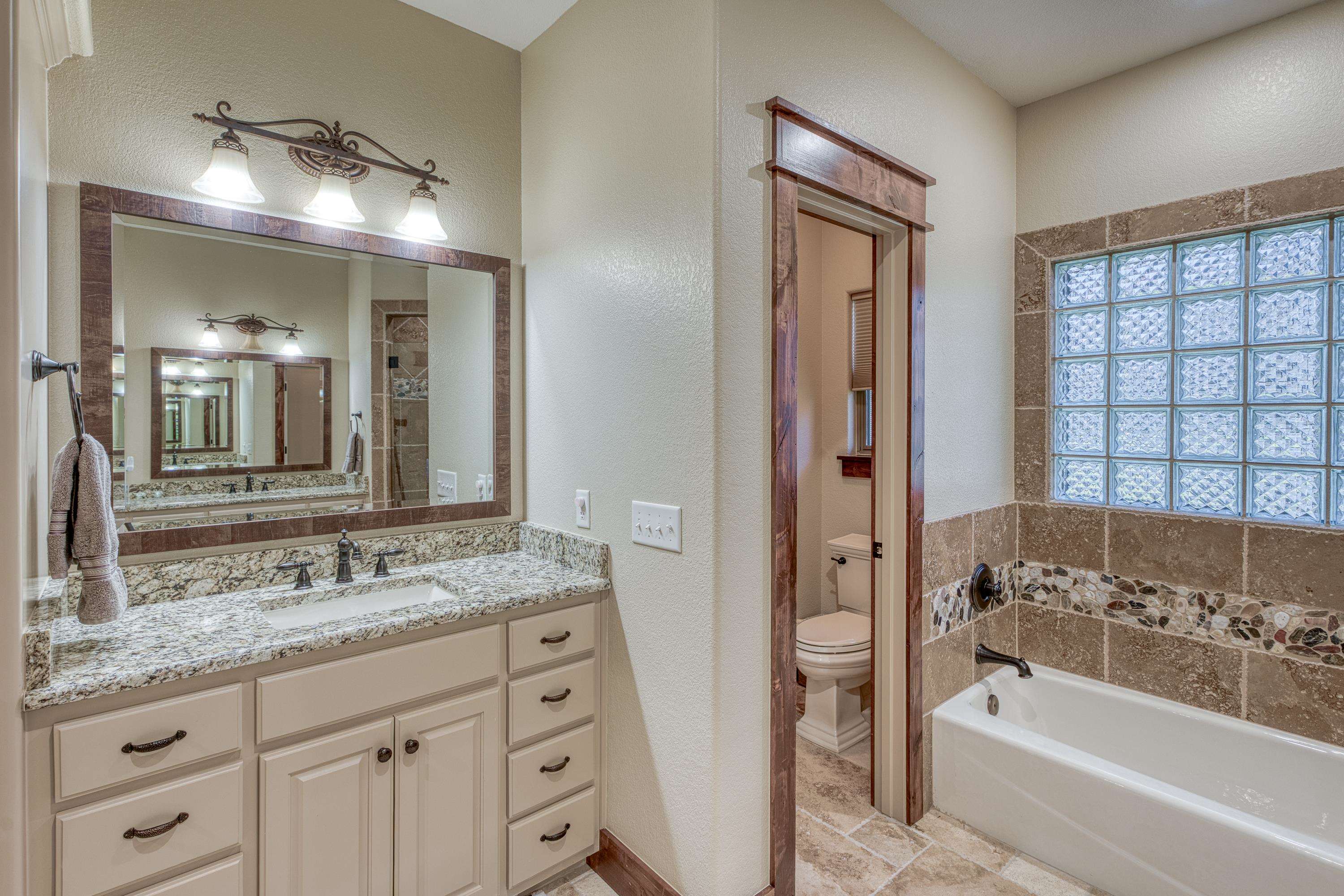 206 River Ranch Road Kingsland, TX 78639 - Photo 19 of 30 a bathroom with a granite countertop tub a sink and a large mirror