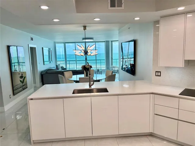 a kitchen with kitchen island granite countertop a sink and white cabinets