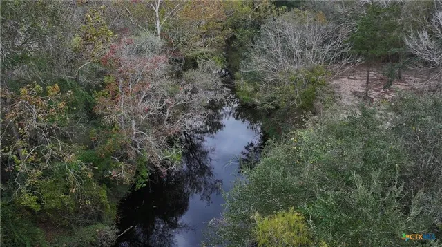 an aerial view of residential house with outdoor space and trees all around