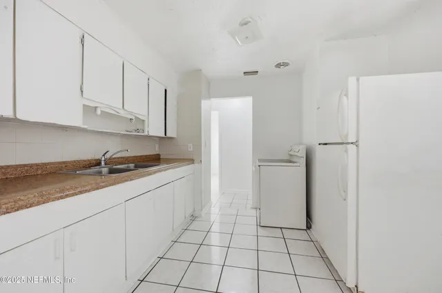 a kitchen with a sink a refrigerator and cabinets