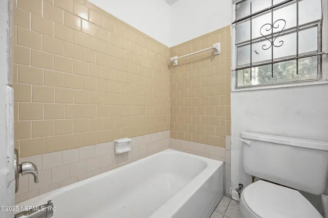 a bath room with a toilet a bath tub and a shower