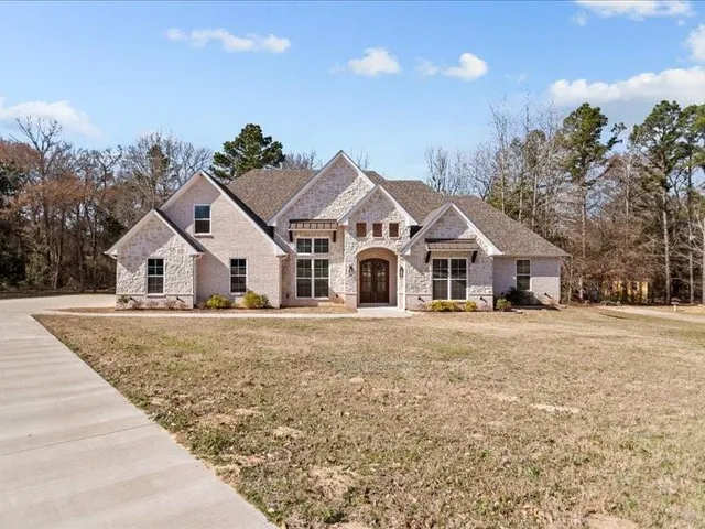 a front view of house with yard and trees in the background