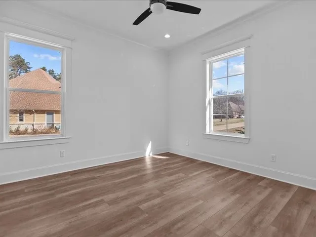 an empty room with wooden floor and windows