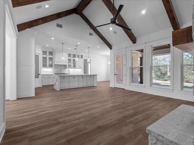 a view of an empty room with kitchen and a window