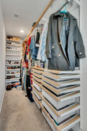 a view of walk in closet with clothes and shoes