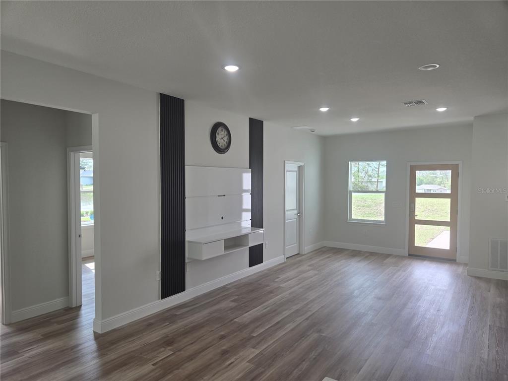 2644 Southwest 162nd Street Road Ocala, FL 34473 - Photo 12 of 47 a view of an empty room and a kitchen with wooden floor