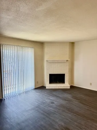 an empty room with wooden floor fireplace and windows