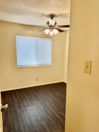 a view of a big room with wooden floor a chandelier fan and a window