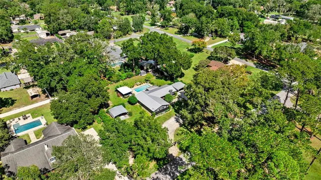 an aerial view of residential house with outdoor space and trees all around