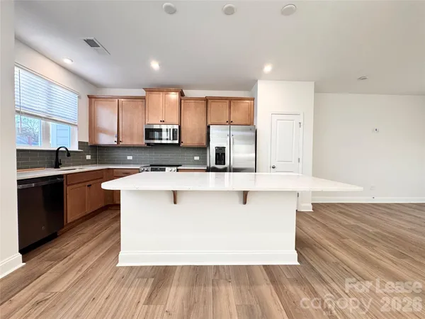 a large kitchen with stainless steel appliances a large counter top a stove and a refrigerator