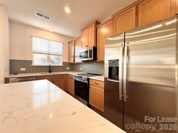 a kitchen with stainless steel appliances granite countertop a refrigerator a stove and a sink with wooden floor