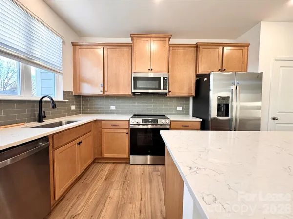 a kitchen with stainless steel appliances granite countertop a stove a sink and a refrigerator