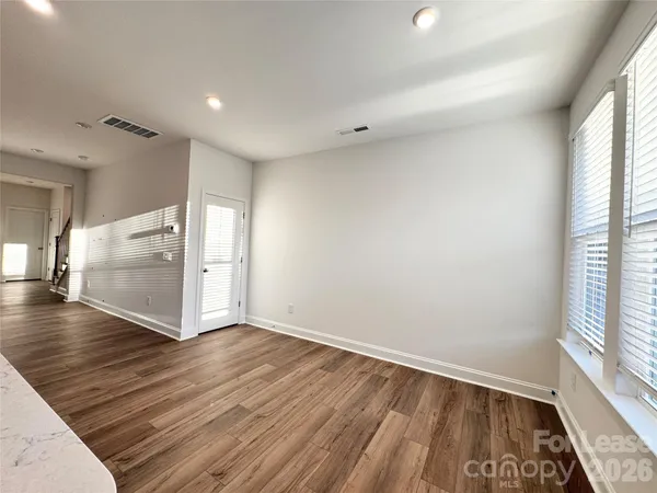 a view of an empty room with window and wooden floor