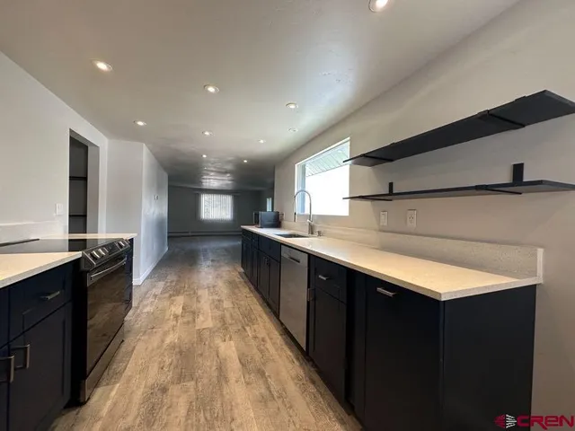 a large kitchen with stainless steel appliances a large counter top a stove top oven a sink and dishwasher