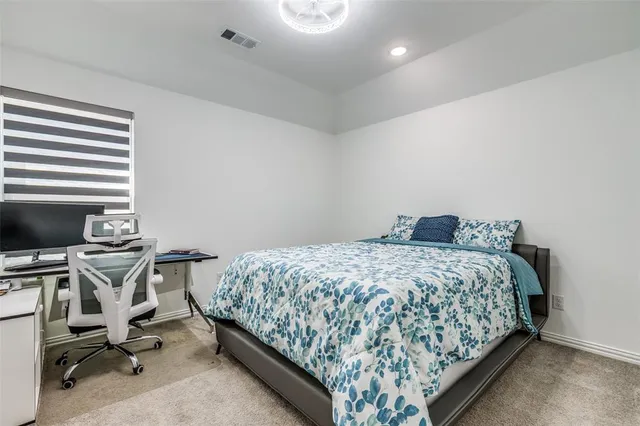 a bedroom with bed and a computer on the desk