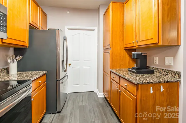 a kitchen with stainless steel appliances granite countertop a refrigerator a sink dishwasher and wooden cabinets with a large window