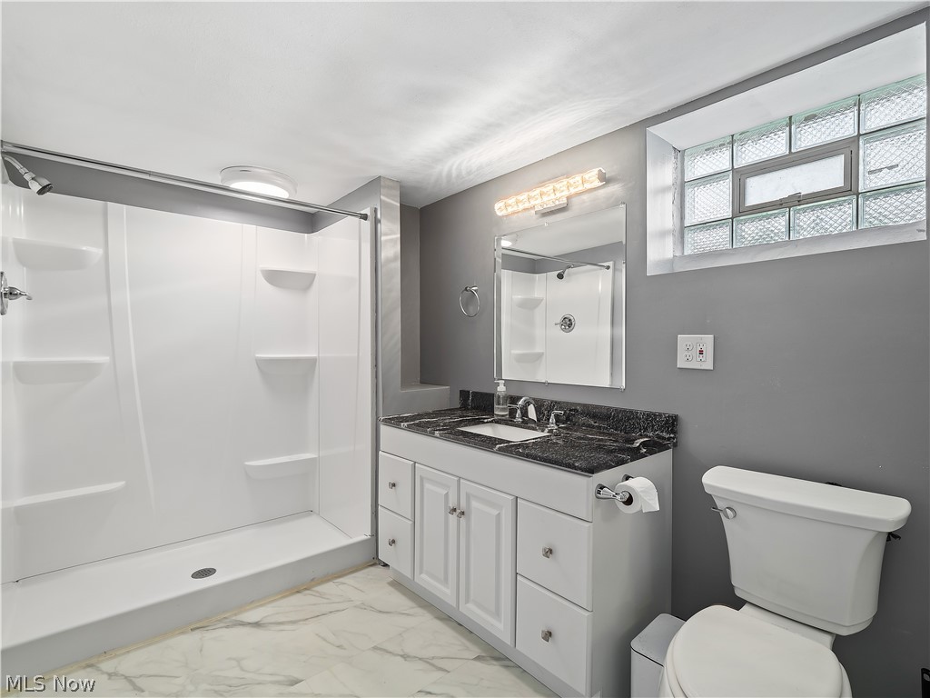 19155 Drake Road Strongsville, OH 44149 - Photo 18 of 29 Basement bathroom with walk in shower, vanity, toilet, and tile floors