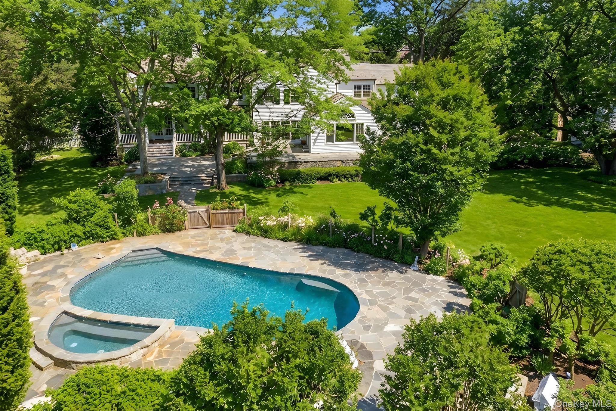 Gorgeous property boasts a saltwater pool with stone waterfall and large hot tub (bocce court and vegetable garden not pictured)