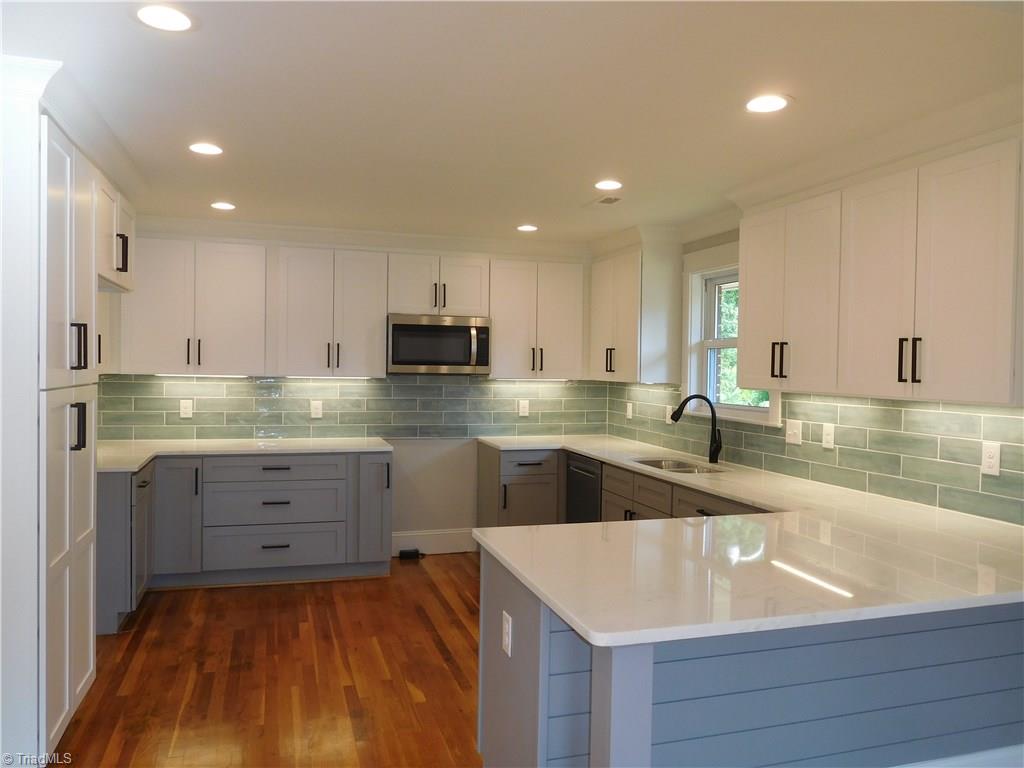 3545 Milhaven Road Winston-Salem, NC 27106 - Photo 9 of 30 All New Beautifully Detailed Kitchen. Kitchen Features: Shaker style gray base cabinets and white wall shaker cabinets w/black pulls, built-in Pantry, Tile Backsplash, Marble Counter tops, under cabinet lights & SS appliances.